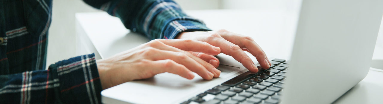 A picture displaying hands of a man working on his laptop.